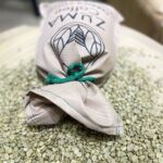 zuma sac of beans on top a pile of green coffee beans