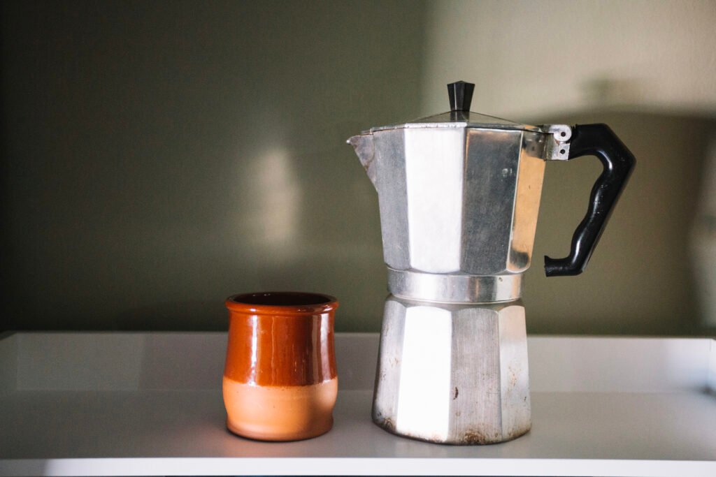 Brown cup beside a silver moka pot - make espresso at home
