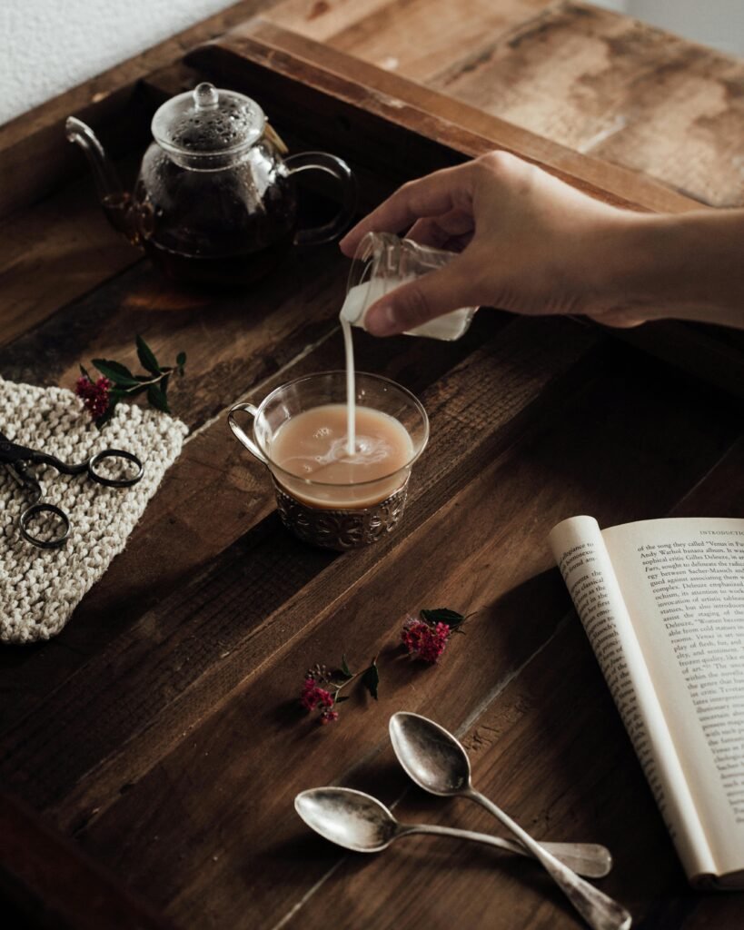 Hand pouring milk into a small glass cup of coffee - how to make coffee at home without a coffee machine