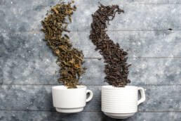 two white cups with dried leaves like double root coffee leaves