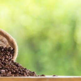 Nigeiran Coffee Beans pouring out of a sack on a wooden table