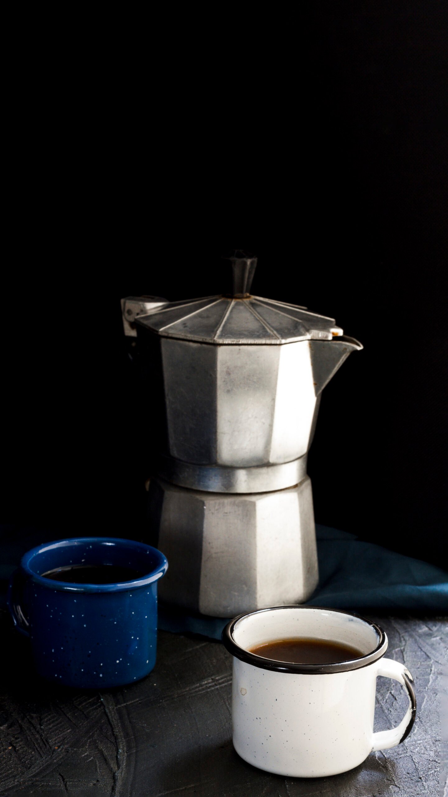 Silver Moke pot over black background with two cups of black coffee - how to brew coffee like a pro